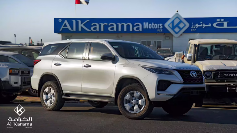 White Toyota Fortuner side profile parked outside Al Karama Motors showroom.