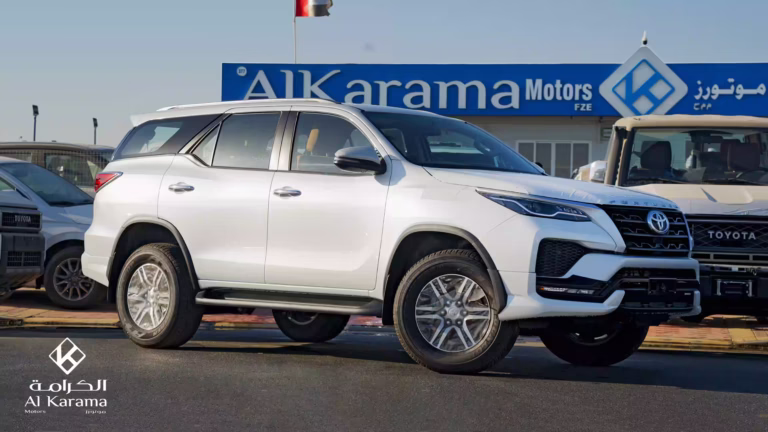 White Toyota Fortuner side profile parked outside Al Karama Motors showroom in Dubai.