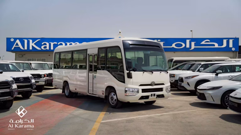 White 2026 Toyota Coaster Bus 4.2L DLX front-side view at Al Karama Motors Dubai